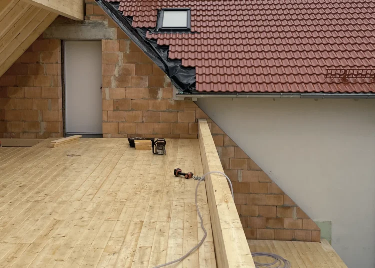 Dachboden eines Neubaus mit frisch verlegtem Bretterboden, Ziegelmauerwerk und Werkzeug auf der Baustelle