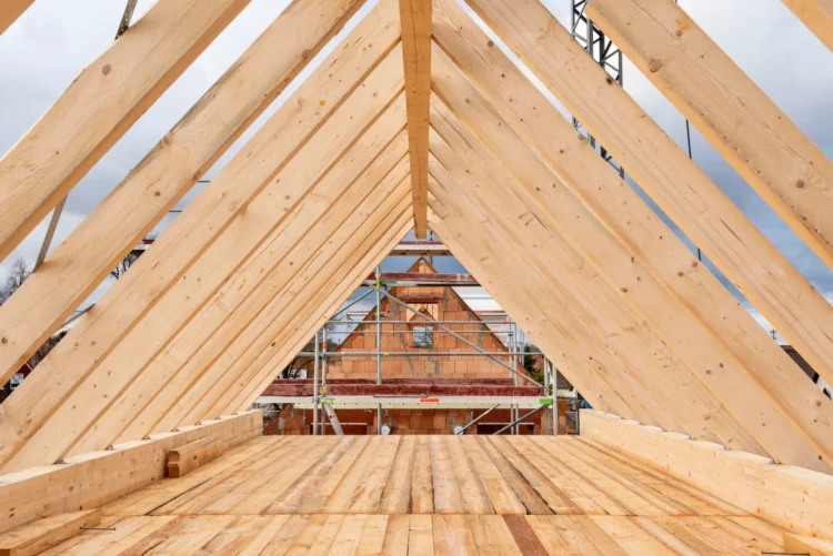 Rohbau eines hölzernen Dachstuhls mit sichtbaren Sparren und Bretterboden